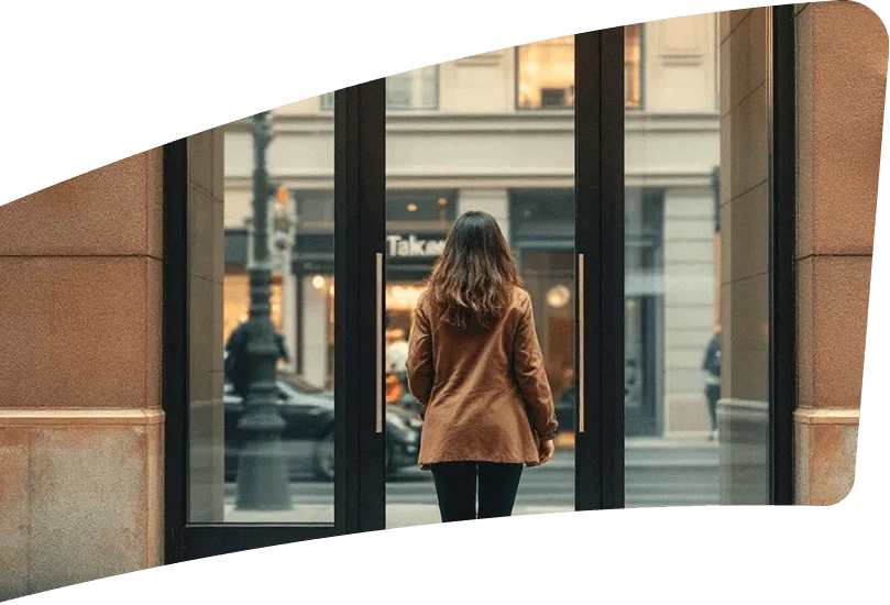 Persona de espaldas frente a una puerta de vidrio en un entorno urbano.
