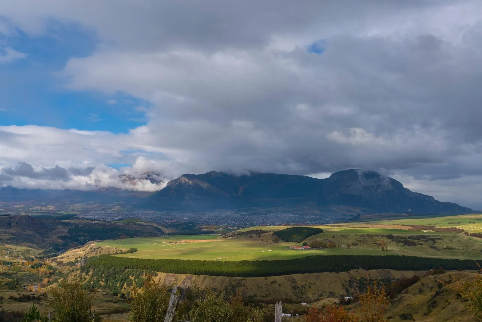 Paisaje de Coyhaique con cerros, campos y cielo nublado en la Patagonia.