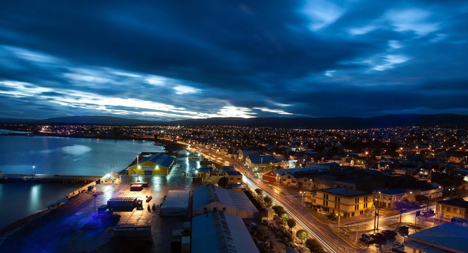 Costanera iluminada de Punta Arenas al anochecer junto al Estrecho de Magallanes.