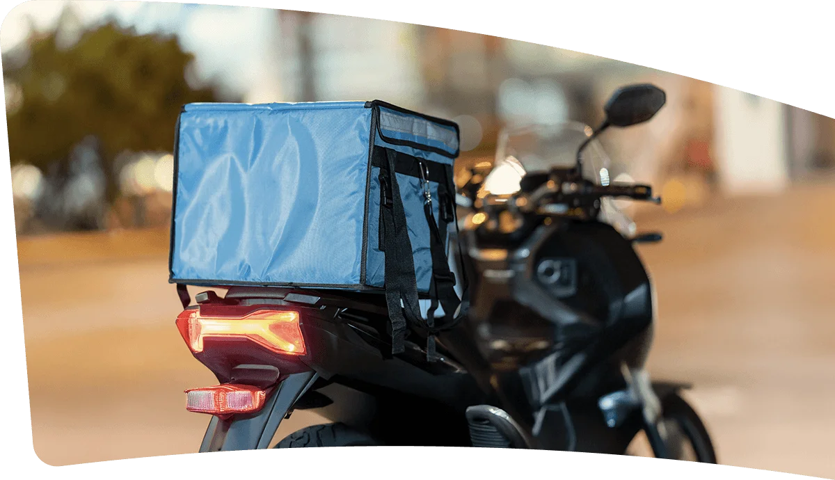 Motocicleta estacionada con una caja de reparto azul en la parte trasera.